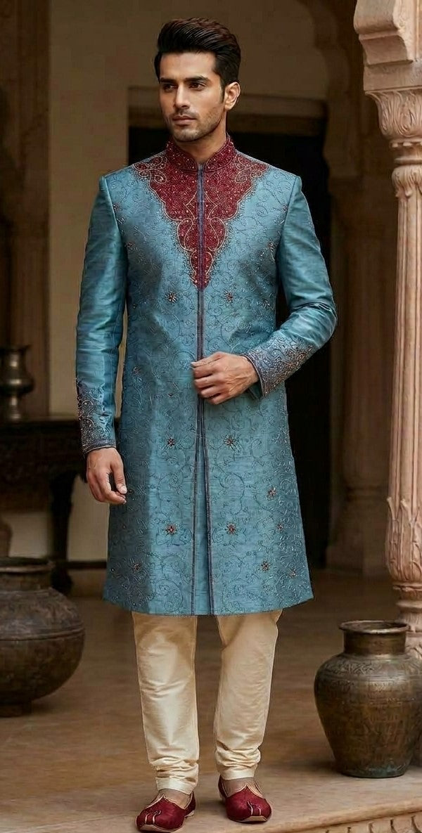 Men's blue sherwani with floral vine pattern, burgundy stand collar and neckline, and patterned cuffs
