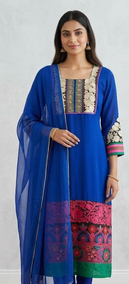 Blue embroidered salwar kameez with cream floral neckline and sleeve details, pink and green hem borders, and a blue draped dupatta