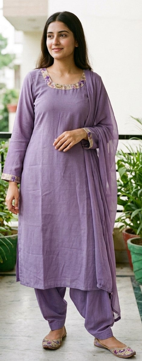 Model wearing a purple long-sleeve kameez with decorative neckline and cuff trim, purple salwar pants and a draped purple dupatta.
